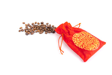 Coffee beans spilled from a red silk bag close-up with white background