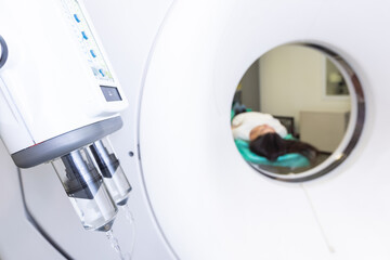 Pretty, young woman goiing through a Computerized Axial Tomography CAT Scan medical test examination in a modern hospital