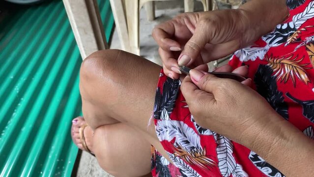 Mature Asian woman trimming excess skin and hangnails of her fingers by herself. Close ups