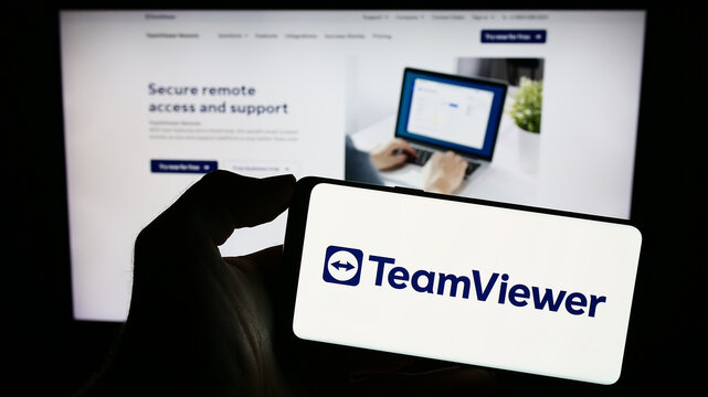 Stuttgart, Germany - 09-13-2023: Person holding cellphone with logo of German software company TeamViewer SE on screen in front of business webpage. Focus on phone display.