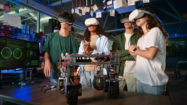 Group of young people in VR glasses discussing and doing experiments in robotics in a laboratory. Robot on the table