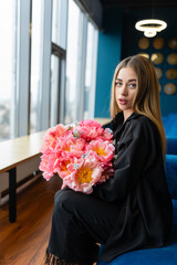 Woman for participating in charitable event receives bouquet as token of appreciation. Female employee sits with flowers in office lounge room