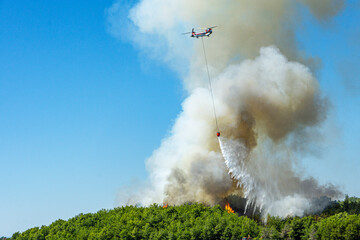 tragic view of forest fire and helibucket which  is a specialized bucket suspended on a cable...