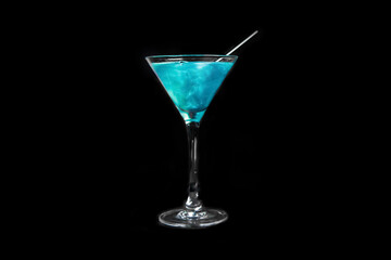 A martini glass with a blue alcoholic beverage and a straw on a black background