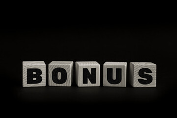 Word BONUS written with wooden cubes. Studio shot of some arranged wooden blocks with a textual message.