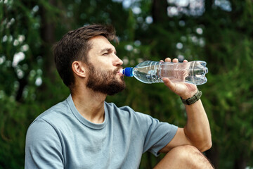Drinks water break athlete fitness exercises for cardio and health.   A man in sportswear doing a workout.  A sporty confident person warming up.