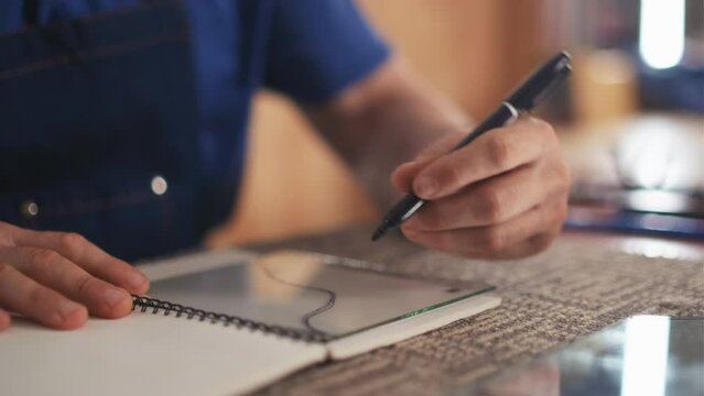 Cropped shot of male left-handed specialist using highlighter to draw line on piece of glass while sitting at his workplace