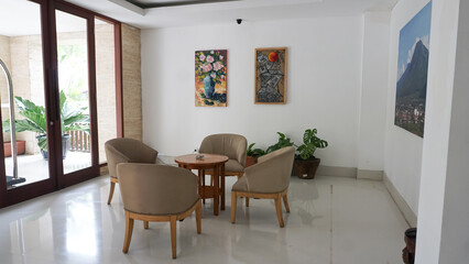 Minimalist interior design of living room with cream colored chairs and a landscape painting background
