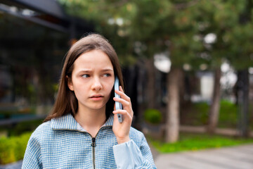 headshot teenager girl calling and speaking on smartphone walking on street