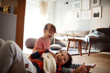Young caucasian brother and sister playing and having fun together in the living room