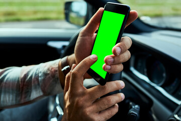 Young man using his smartphone while driving his car in the city