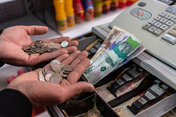 Hands of a man counting Colombian money at a cashier counter