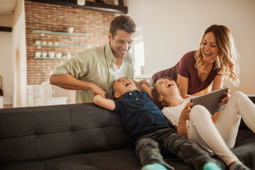 Young caucasian family using a tablet on the couch in the living room