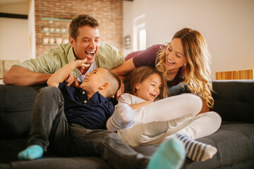 Young caucasian family having fun and being playful on a couch in a living room