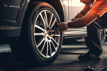 Professional mechanic changing car tyres in auto repair service center. Technician man working at auto repair service center. Changing tire shop. Repair or maintenance auto service.