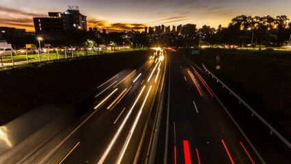 Trail of light caused by vehicular traffic in Highway with buildings from downtown in the background, in Marília,