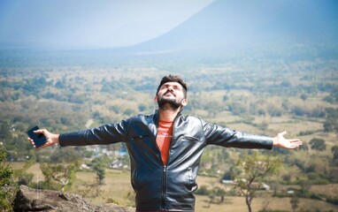 Beautiful Handsome Indian Man enjoying the breeze from a valley view point tourist location