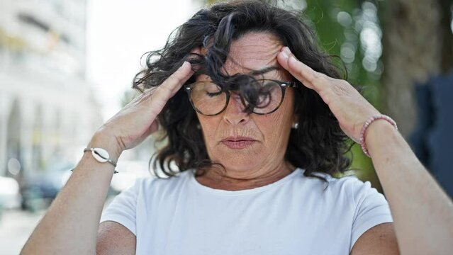 Middle age hispanic woman suffering for headache at park