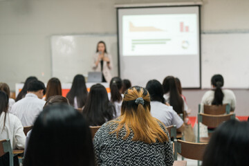 Rear view of college students listen to teacher teaching and explaining lesson in classroom