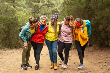 Happy women with different ages and ethnicities having fun walking in the woods - Adventure and travel people concept