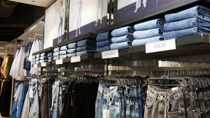 Many various jeans for women hanging on the rags in a clothing store