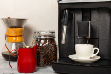 Modern coffee machine with a cup on the kitchen table. Coffee house. Modern espresso coffee machine with a cup in the kitchen. Preparation of a fragrant hot drink. Place for text.Copy space.