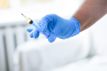 Hand in blue glove holding syringe with copy space. Syringe with sharp needle in hand. Medical treatment concept. Laboratory backgrouund. Medicare concept. Vaccination concept.