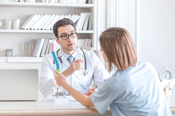 Male doctor orthopedist explaining to his female patient with serious neck injury about importance...