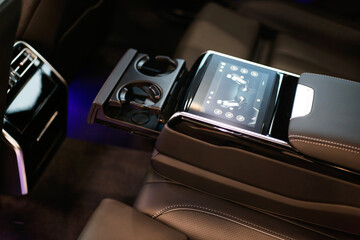 armrest with multimedia display and cup holders in the back row in the interior of a luxury car