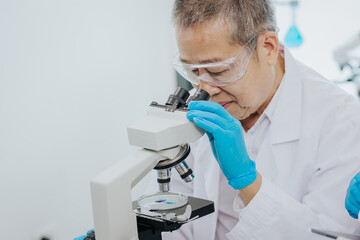 Two Asian scientists in the laboratory or medical personnel looking at a microscope in the lab