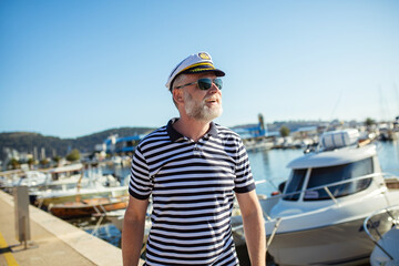 Fototapeta na wymiar Mature man standing near the sea dressed in a sailor's shirt and hat.