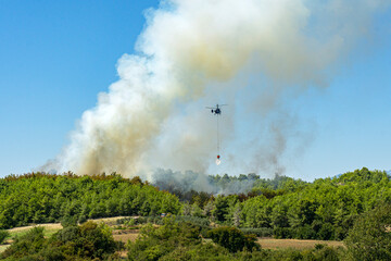 tragic view of forest fire and helibucket which  is a specialized bucket suspended on a cable...