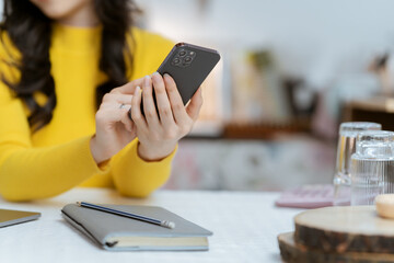 Beautiful Asian woman smiling happily relaxing using laptop technology Take notes Drink a relaxing hot drink while sitting on the table in your room at home.