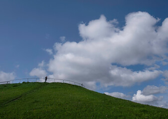 Lonely man on the hill and in the background beautiful white clouds