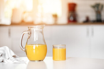 A glass of orange juice on the table, a bright stylish kitchen in the background.