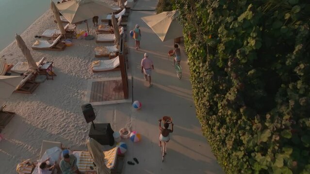 A drone flies over an outdoor pool with a club by the sea, Dubai. People sunbathe, relax in the bar and cafe, swim in the pool.