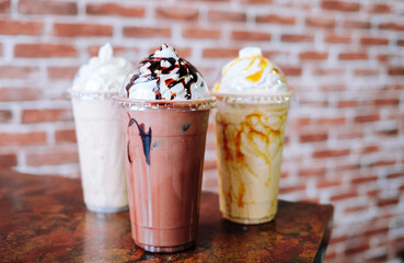Frappe iced coffees sitting on a table against a brick wall