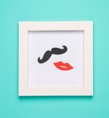 Paper-cut mustache and lips in a white frame on a blue background