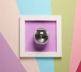 Disco ball in white square frame on colored background. Aesthetic minimal still life. Conceptual...