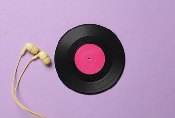 Vinyl record with headphones on magenta pastel background. Top view