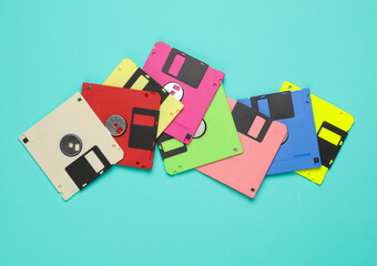 Many colored floppy disks on blue background. Computer technology 80s. Top view.