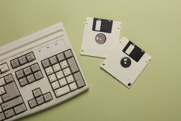 Retro keyboard and floppy disks on a green background. Top view