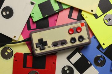 Old joystick on background of many colored retro floppy disks. Retro technology. Top view