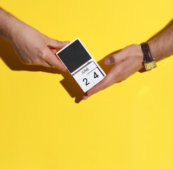 Man's hand holding wooden block calendar with date June 24 on yellow background
