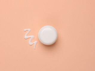 Mockup of a white jar with a smear of cream on a pink background. Top view. Beauty concept