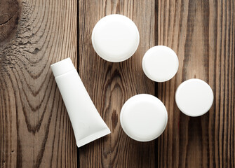 White cream tube and jars on wooden background. Creative layout. Template for design. Mockup. Minmal beauty concept.