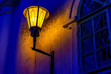 Old vintage street lamp in selective focus glow at night.Magic lamp with warm yellow light in blue...