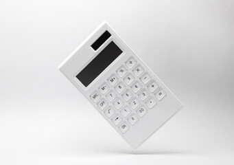 White calculator levitates on gray background with shadow