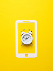 Paper-cut smartphone icon with alarm clock on a yellow background
