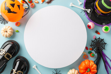 Enjoyable kids' Halloween jubilation idea. Overhead sight of candies, youngster clothing components and spooky decor on light blue backdrop, offering empty circle for promotional material or text